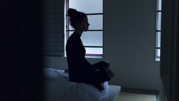 A woman sits in the dark, struggling before seeking treatment for depression.